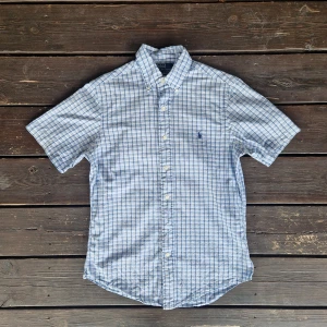 Ralph lauren skjorta small - 📊 Färg: Vit & Ljusblå  📏 Storlek: Small (S)  📐 Mått: Längd - 73cm Axelbredd - 42cm  ♻️ En kortärmad vit och ljusblå Ralph lauren skjorta i storlek S. I väldigt bra skick, inga fläckar, hål eller defekter! Perfekt nu när det börjar bli varmare och sommaren kommer!☺️  👕 Material: 100% Bomull