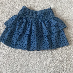 Blå volangkjol med prickigt mönster från Zara - Supersöt blå kjol från Zara med volanger och små svarta blommor. Säljer pga att den är för liten. Storlek 11-12 år.  Köparen står för frakten🤗