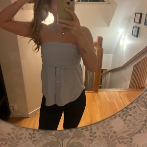 Ljusblå tubtopp med knappar - Säljer en stilren ljusblå tubtopp med knappar framtill. Perfekt för varma dagar och kan enkelt matchas med olika outfits. Säljer den då den inte passar längre, men den är endast använd 2 gånger.