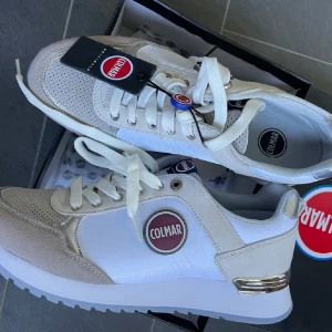 Vita och beige sneakers från Colmar 41 - Snygga sneakers från Colmar i vitt och beige med snörning. Skorna har en stilren design med Colmar-logga på sidan och en bekväm sula. Perfekta för en avslappnad stil.