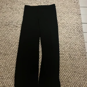 Svarta byxor från Kappahl - Snygga svarta byxor från Kappahl i storlek 152. De har en klassisk rak passform och är perfekta för en stilren look. Byxorna är tillverkade i ett bekvämt material som passar till många olika tillfällen.