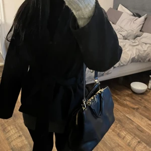 Michael kors väska - Snygg svart handväska med dragkedja och gulddetaljer. Perfekt för att bära dina dagliga nödvändigheter med stil. Väskan har en elegant design och är lätt att matcha med olika outfits.