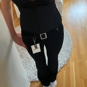 Svarta lågmidjade jeans - Svarta low-/midwaist jeans från ONLY tall. Jeansen har ett skärp/bälte som följer med som en snygg detalj men som går att ta bort också då det inte är fastsytt i byxan! De är helt nya och aldrig använda, med lappen kvar! De är i längden 36