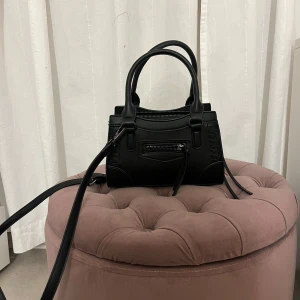 Svart handväska med dragkedja - Snygg svart handväska från Gina Tricot med dragkedja och stilrena detaljer. Väskan har både handtag och en avtagbar axelrem för flexibilitet. Använd fåtal gånger!!!💕
