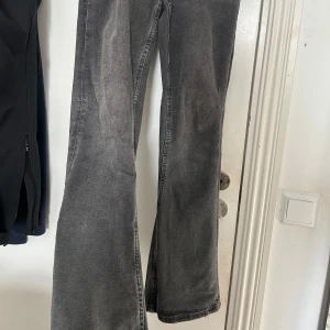 Grå bootcut jeans från Gina Tricot - Snygga grå bootcut jeans från Gina Tricot. De har en klassisk femficksdesign och en bekväm passform. Perfekta för en avslappnad stil med en touch av retro. Dessa är lågmidjade i storlek 158.