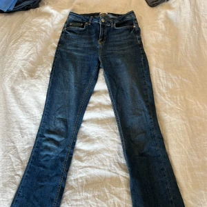 Blå jeans från Grunt - Snygga blå jeans från Grunt med klassisk femficksdesign och knappgylf. De har en bootcut-stil som ger en retro känsla. Perfekta för en avslappnad look. Smala i storleken.
