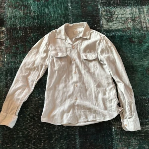 Grå långärmad skjorta från borriello - Säljer en stilren grå skjorta från Borriello. Skjortan har långa ärmar och två bröstfickor med knappar. Perfekt för en klassisk och avslappnad look. Sitter som s. 