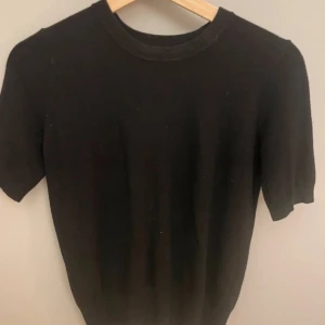 Svart t-shirt från Zara - Säljer en stilren svart t-shirt från Zara i storlek S. Den har en klassisk rund hals och korta ärmar, perfekt för en minimalistisk look. Passar till alla tillfällen och är lätt att matcha med andra plagg. Stickad är den utan noppror då den knappt är använd 