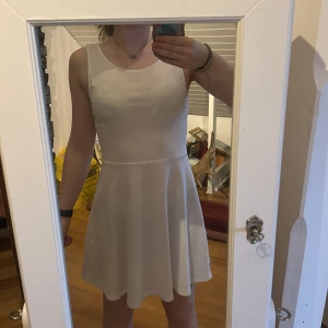 Vit klänning från H&M - Säljer en stilren vit klänning från H&M. Klänningen är ärmlös med en rund halsringning och har en fin detalj med öppen rygg. 