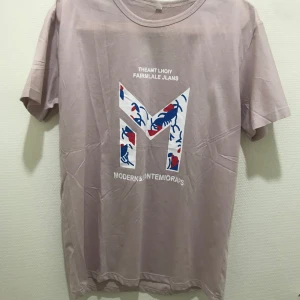  t-shirt med tryck - Säljer en  t-shirt med ett stort grafiskt tryck i blått och rött på framsidan. T-shirten har en rund halsringning och korta ärmar. Perfekt för en avslappnad stil.  Helt ny 