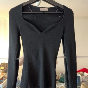 Svart ribbad tröja med v-ringning - Snygg svart ribbad tröja med v-ringad hals. Perfekt för en stilren look. Långärmad design som passar bra till både jeans och kjol.