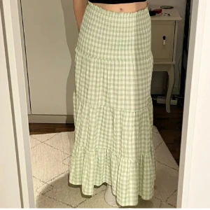 Grön rutig långkjol - Snygg grön rutig långkjol med smockdetaljer i midjan. Perfekt till sommaren och går även jättebra att använda som klänning😍