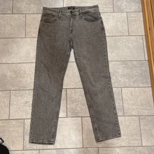 Grå jeans från Jack & Jones - Snygga grå jeans från Jack & Jones med en klassisk design. De har en rak passform och är tillverkade i slitstarkt denim. Perfekta för en avslappnad stil.