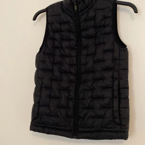 Svart dunväst från Everest - Snygg svart dunväst från Everest med dragkedja framtill. Perfekt för lager-på-lager under kyliga dagar. Västen har en quiltad design som ger en stilren look.