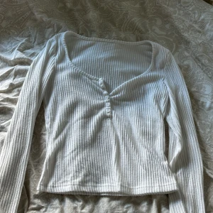 Vit ribbad tröja med knappar - Säljer en vit ribbad tröja med u-ringning och knappar framtill. Tröjan har långa ärmar och är i så mysigt material💕mysig som pyjamas tröja eller bara vanligt💕 helt oanvänd💕