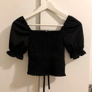 Svart kortärmad topp - Snygg svart topp med puffiga korta ärmar. Köpt utomlands. Står storlek M men passar även mig som har XS då den sitter tight. För frågor eller fler bilder är det bara att skriva till mig 💕