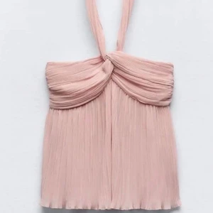 Plisserad rosa halterneck topp - Säljer en superfin plisserad rosa halterneck topp med twistad detalj framtill. Toppen har en luftig och flowy känsla, perfekt för varma dagar eller när du vill känna dig extra söt. Passar lika bra till jeans som till kjol!