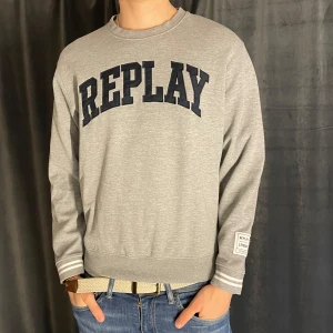 Grå sweatshirt från Replay - Säljer en stilren grå sweatshirt från Replay med stor mörkblå logga över bröstet och patch på ärmen. Tröjan har rund halsringning och långa ärmar. Perfekt för en avslappnad och trendig look. Skick 8/10✅ Pris kan diskuteras vid snabb affär💸