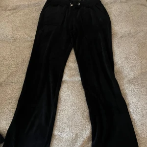 Svarta velourbyxor från Juicy Couture - Säljer ett par svarta mjukisbyxor från Juicy Couture i mjuk velour. Byxorna har dragsko i midjan, fickor fram och bak med knappar samt diskret broderad logga på ena fickan. Kom till användning 3 gånger sen lämnade i garderoben 💙