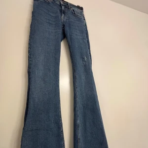 Blå bootcut jeans - Säljer ett par klassiska blå bootcut jeans med normal passform. Jeansen har fem fickor, dragkedja och knapp framtill samt en liten sliten detalj på ena benet. Använt 1 gång💞
