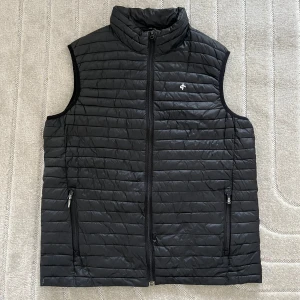 Svart dunväst med dragkedja - Snygg svart dunväst från Peak Performance med hög krage och hel dragkedja framtill. Västen har två fickor med dragkedja och diskret logga på bröstet. Perfekt för lager-på-lager. • Storlek L • Frakt tillkommer  • Har du några frågor är det bara att skicka ett meddelande, så svarar jag så fort jag kan.☺️ Ha en fin dag!💕♻️