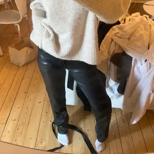 Säljer ett par svarta skinnbyxor med låg midja och slim passform. Byxorna har klassisk femficksdesign och sitter tight längs benen. Perfekta för en trendig och stilren look.