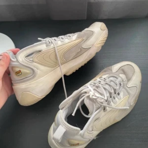 Nike skor  - Nike zoom 2k super sköna skor, färgen är lite smutsig men tror det skulle bli som ny med en tvätt Insidan av höger sko har en liten skada också  Men utöver de är skorna i jätte bra skick