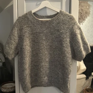Grå stickad tröja med kort ärm - Mysig grå stickad tröja med korta ärmar och rund halsringning. Tröjan har en avslappnad passform och ribbade muddar vid ärmslut och nederkant. Perfekt för lager-på-lager och enkel att matcha med olika outfits. I storlek xl men passar mig bra som har s-m annars ☺️