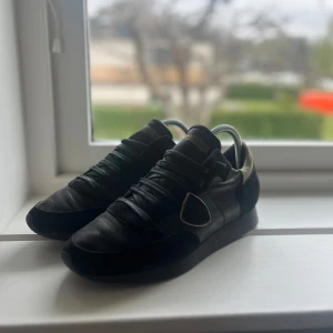Philippe Model trpx  - Säljer ett par svarta sneakers från Philippe Model med detaljer i mocka och skinn. Det är en unik kombo av färger som gör det unikt och snyggt. Strl 40! Använda vid få tillfällen!
