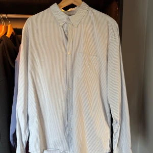 Blåvit randig skjorta från J.Lindeberg - Klassisk blåvit randig skjorta från J.Lindeberg. Slim fit. Superfint skick och lite tunnare i tyget vilket gör att den är perfekt för sommaren! 