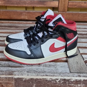 Nike Air Jordans svart, vit och röd - Säljer ett par klassiska Nike Air Jordans med svart, vit och röd färg. Skorna har högt skaft, svart snörning och den ikoniska röda swoosh-loggan på sidan. Perfekta för dig som gillar streetwear och sneakers med attityd.har varit i bruk runt 1 år. Är äkta. Boxen är tyvär borta. Du betalar för frakt 