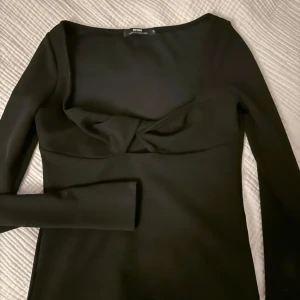 Svart långärmad topp med twist-detalj - Långärmad topp med snygg twist-detalj framtill och djup urringning. 🖤