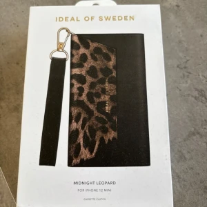 Leopardmönstrad plånbokskal från Ideal of Sweden iPhone 12 mini  - Snygg leopardmönstrad plånbokskal från Ideal of Sweden. Den har ett stilrent svart och leopardmönstrat yttre med plats för kort och mobil. Perfekt accessoar för att hålla dina saker organiserade och trendiga. Helt ny! Till iPhone 12 mini 