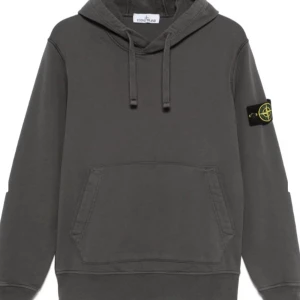 Grå hoodie från Stone Island - Snygg grå hoodie från Stone Island med klassisk känguruficka och justerbar huva. Den har en ikonisk logotyp på ärmen som ger en cool touch. Perfekt för en avslappnad stil. har ingen egen bild för tillfället men kan lösas snart. Den är i storlek L.   Tar även byten!