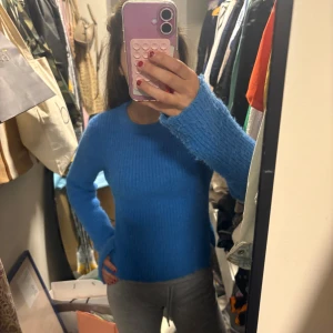 Blå stickad tröja med slits i sidan - Säljer en blå stickad tröja med rund halsringning och långa ärmar. Tröjan har en liten slits i sidan och är mjuk och mysig, perfekt för kyligare dagar. Enkel och stilren design som passar till det mesta. Skriv för fler bilder och info🥰