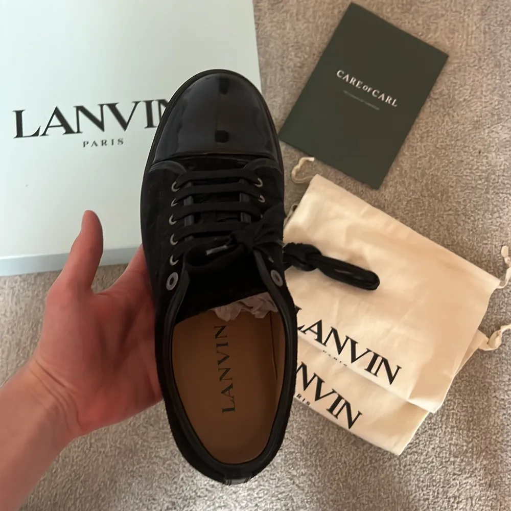 Säljer ett par svarta sneakers från Lanvin med snygg lackad tå och ovandel i mocka. Skorna har svarta skosnören, rund tå och platt sula. Kommer med originalkartong, dustbags och extra skosnören. Det vill säga allt og hänger med. Om ni vill ha mer bilder eller har några funderingar är det bara att kontakta mig.. Kengät.