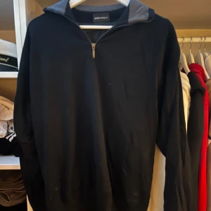 Svart halvzip tröja med krage - Svart långärmad tröja med halv dragkedja och krage. Tröjan har en normal passform och är fodrad på insidan för extra värme. Perfekt för kyligare dagar och enkel att matcha med jeans eller chinos.