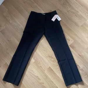 Svarta kostymbyxor från Nelly - Snygga svarta kostymbyxor från Nelly med normal passform och raka ben. Byxorna har hällor för bälte och diskreta sidfickor. 