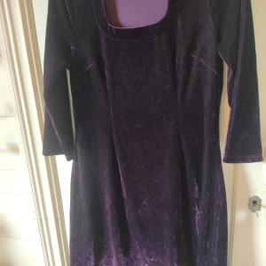 Mörklila sammetklänning - Säljer en mörklila klänning i mjuk sammet med trekvarts ärm och fyrkantig urringning. Klänningen är lite figursydd då den går in vid midjan och går sen ut lite i en A-line kjol. Det står storlek S på etiketten men jag skulle säga att den är mer av en M.