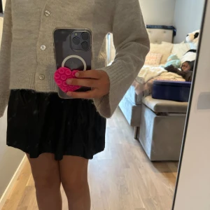 Svart kortkjol från Gina Tricot - Supersnygg svart skinnskjol från Gina Tricot med glansig finish och bred resår i midjan. Kjolen har en enkel och stilren look som är lätt att matcha med olika toppar. Perfekt för dig som gillar trendiga och bekväma plagg.