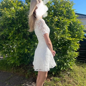 Vit spetsklänning med kort ärm - Superfin vit klänning med kort ärm från bubbleroom, nypris=1000kr, den är använd 2 gånger. Klänningen är gjord i spets med blommigt mönster, figurnära passform upptill och lite utsvängd kjol. 