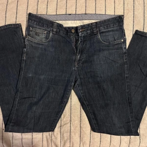 Canali mörkblå jeans – strl 50 - Canali mörkblå jeans – strl 50 Mörkblå jeans från Canali med klassisk femficksdesign och diskret broderad logga på myntfickan. Raka ben, normal passform och mjukt bomullsjeansmaterial. Tidlös och stilren design. Skick: God condition, endast ett litet slitage mellan benen (knappt synligt)