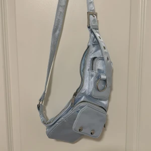 Ljusblå axelväska/crossbody väska  -  ljusblå axelväska/crossbody väska med silvriga detaljer.