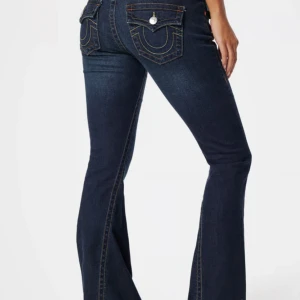 Mörkblå bootcut jeans från True Religion - Säljer dessa jeans då jag inte kan använda dom för att dom är för stora. dom har en liten fläck på låret men knappt något man tänker på. dom är dock också ganska söndriga längst ner vid fötterna då dom varit för långa. pris kan diskuteras, skriv också för bilder