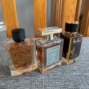 Tre herrparfymer med träiga toner - Säljer tre stilrena herrparfymer: Your Touch från Alhambra i fyrkantig flaska med svart kork, Alvernum Tobacco & Amber i elegant glasflaska med silverdetaljer och Rachba Wood Intense i mörk flaska med guldtext. Alla har varma, träiga och kryddiga doftnoter.