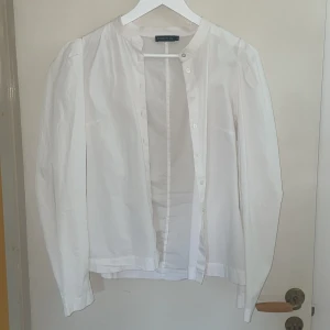 Vit skjorta från Stoch LM - Snygg vit skjorta från Stoch LM med klassisk rund hals och knappar framtill. Skjortan har lång ärm och är tillverkad i mjuk bomull, perfekt för en clean och fräsch look. Passar dig som gillar enkel och stilren design.