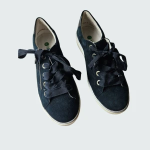 Marinblå sneaker i mocka - Nya och helt oanvända snygga mörkblå sneakers i mocka från Remonte i storlek 38. Skorna har breda snören, en vit platt sula och en cool dragkedjedetalj på sidan. Perfekt till sensommaren och hösten för dig som gillar stilrena och moderna skor. Nypris 900 kr. Rökfritt, men katt finns i hemmet.