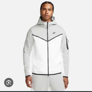 Nike Tech Fleece vit/grå hoodie - Säljer en Nike Tech Fleece hoodie pågrund av att den aldrig används, den har enbart användts 1 gång så tröjan är som ny! Skriv för fler bilder!