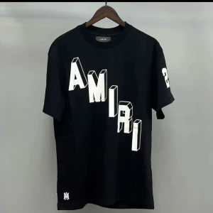Svart AMIRI t-shirt med tryck - Svart t-shirt från AMIRI med stor vit 3D-logga diagonalt över framsidan och siffran 23 på ärmen. Rund hals och korta ärmar. Materialet ser ut att vara mjuk bomull, perfekt för en chill och stilren look.