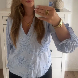LjusBlå v-ringad blus ZaRA - Intressekoll. Säljer en ljusblå skjorta med tunna vita ränder och stora blommiga broderier. Skjortan har v-ringad hals och långa ärmar med volangdetalj vid mudden.  Jättesnygg blus från Zara och den är endast använd en gång!😍så så snygg till skolstart och hösten. 